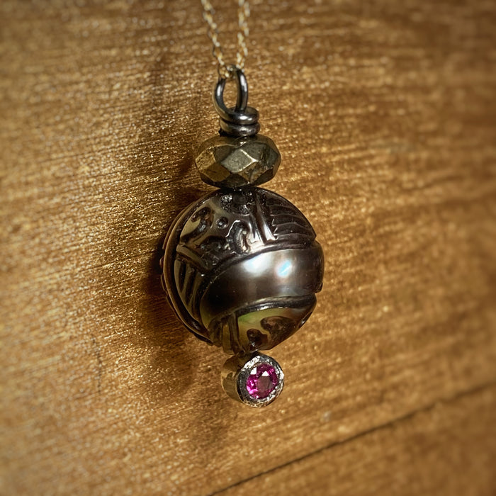 Carved Tahitian pearl pendant with ruby silver and gold